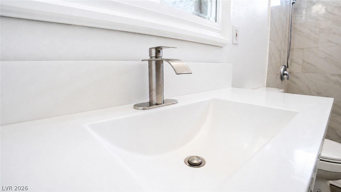 2870 South Sandhill Road Las Vegas, NV 89121 - Photo 50 of 64 A sleek white vanity offers a pristine basin and modern faucet, complementing the bright bathroom.