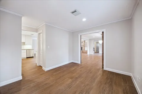 a view of an empty room with wooden floor and a fireplace
