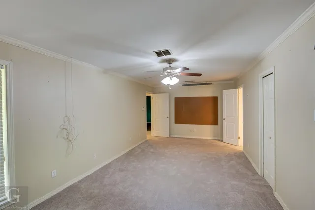 a view of an empty room with a chandelier fan