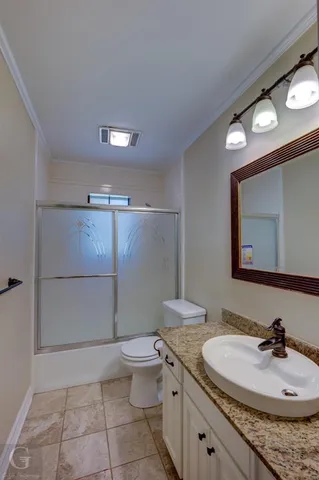 a bathroom with a granite countertop sink a toilet a mirror and shower