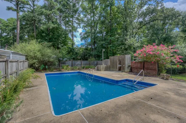 a view of pool with lawn chairs and plants