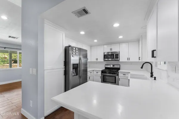 a kitchen with stainless steel appliances granite countertop a refrigerator stove microwave and sink