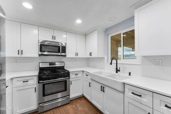 a kitchen with cabinets stainless steel appliances a sink and a window
