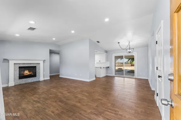 an empty room with wooden floor fireplace and windows