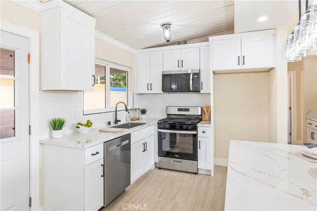 a kitchen with stainless steel appliances a stove a sink a stove a microwave a refrigerator a sink and cabinets