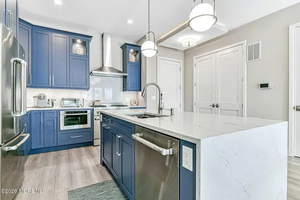 a kitchen with stainless steel appliances granite countertop a sink a stove and a wooden floors