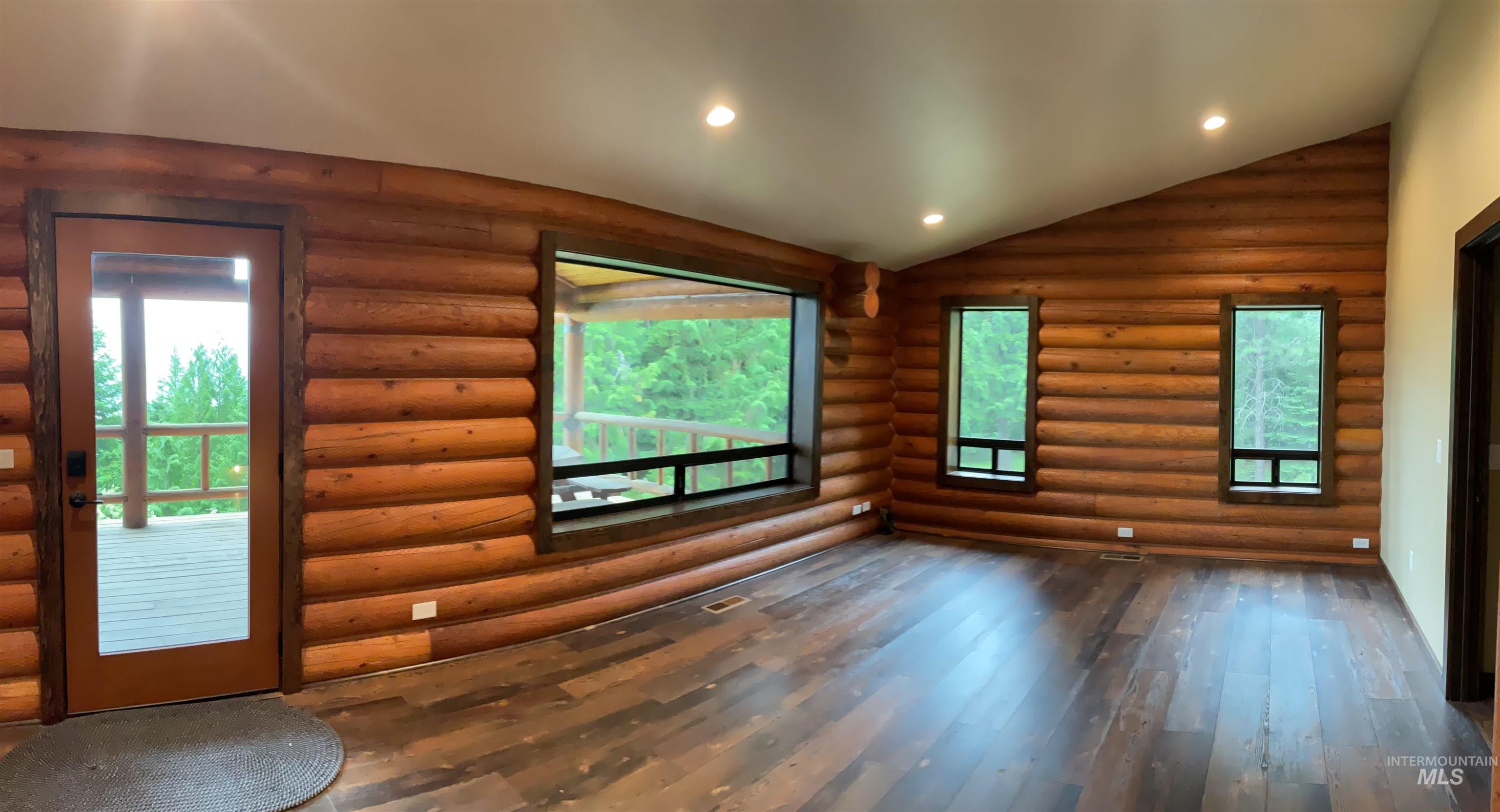 6125 Freeman Creek Road Lenore, ID 83541 - Photo 14 of 44 Interior space featuring log walls, wood-finish flooring, a vaulted ceiling with recessed lighting, and multiple windows