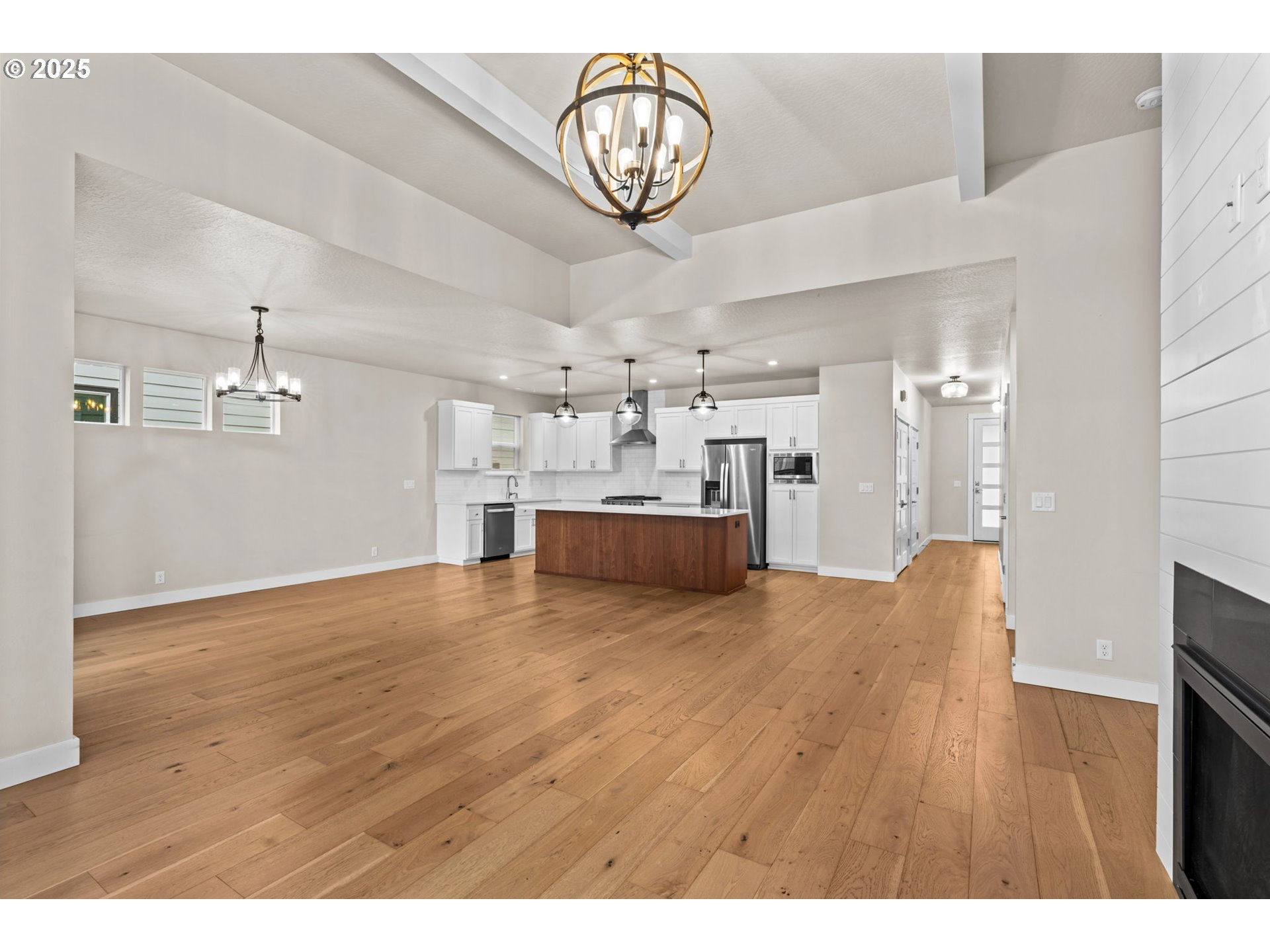 1030 53rd Place Springfield, OR 97478 - Photo 19 of 39 a view of an empty room and kitchen with furniture wooden floor and a chandelier