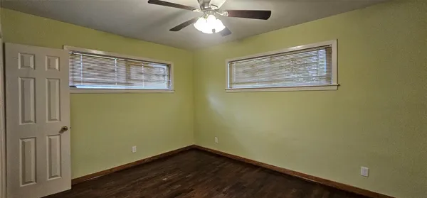 an empty room with wooden floor and fan