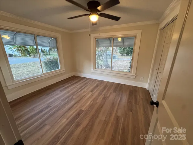 a view of an empty room with wooden floor and a window