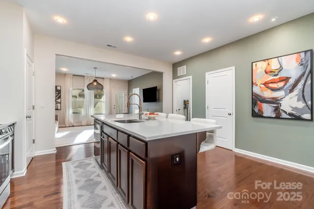 a kitchen with stainless steel appliances a stove a sink a refrigerator and white cabinets with wooden floor