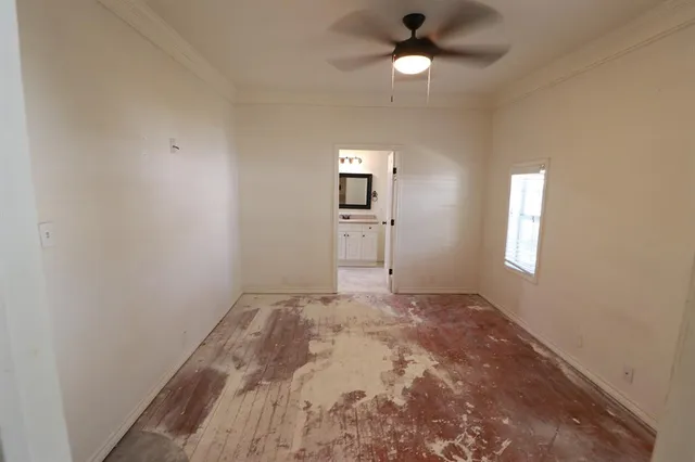 en empty room with windows and ceiling fan