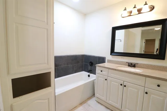 a bathroom with a tub sink and mirror
