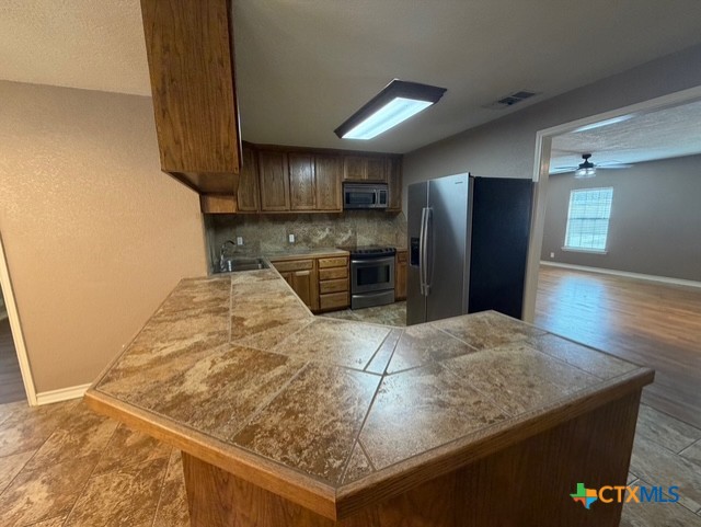 127 Hillcrest Drive Luling, TX 78648 - Photo 8 of 26 a kitchen with stainless steel appliances kitchen island granite countertop a refrigerator a stove and a sink with wooden floor