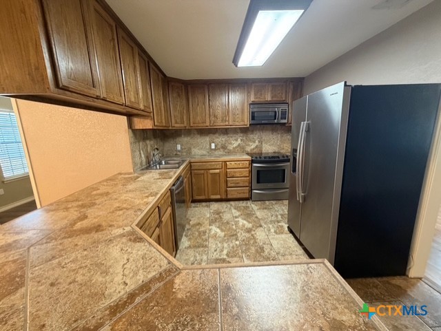 127 Hillcrest Drive Luling, TX 78648 - Photo 9 of 26 a kitchen with stainless steel appliances granite countertop a refrigerator a stove and a sink with wooden cabinets