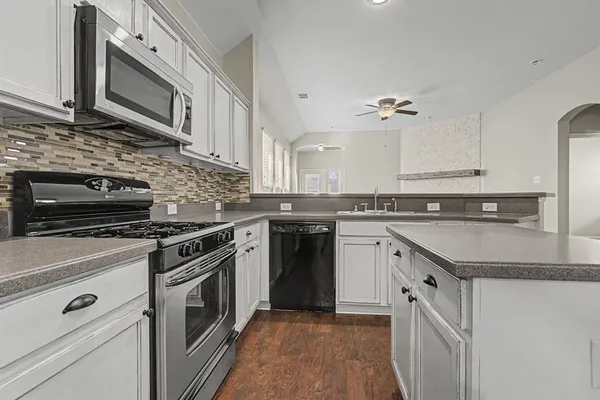 a kitchen with stainless steel appliances granite countertop a stove a sink and a microwave