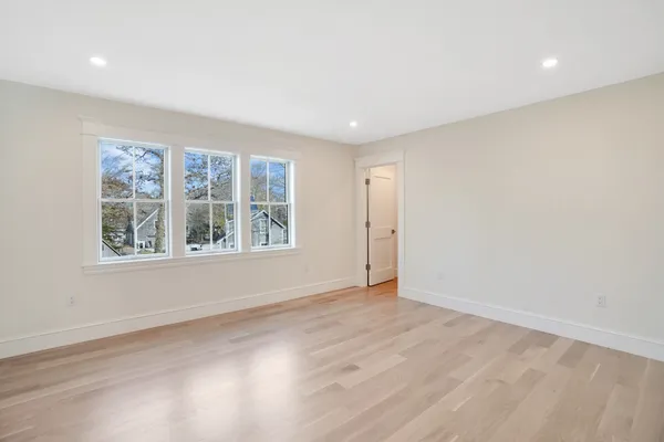 a view of an empty room with wooden floor and windows