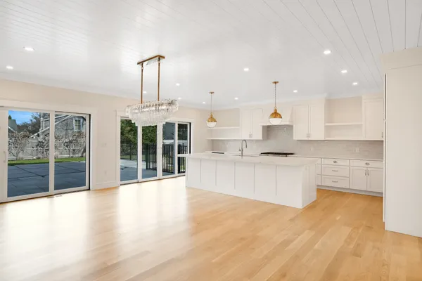 a large kitchen with stainless steel appliances wooden floor and a large window