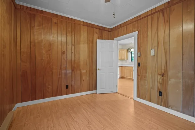a view of an empty room with wooden floor and a bathroom