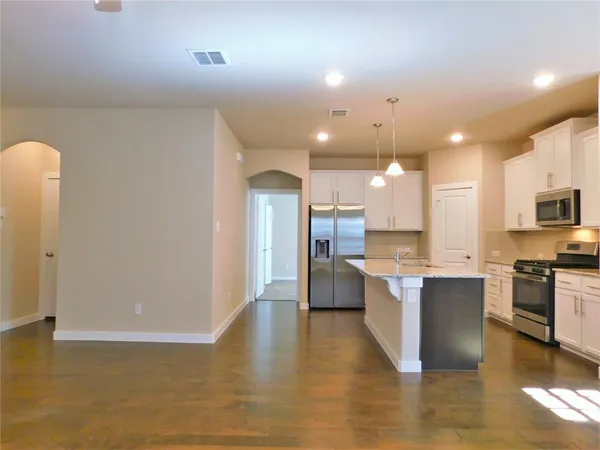 a large kitchen with granite countertop a stove a sink a refrigerator and a microwave