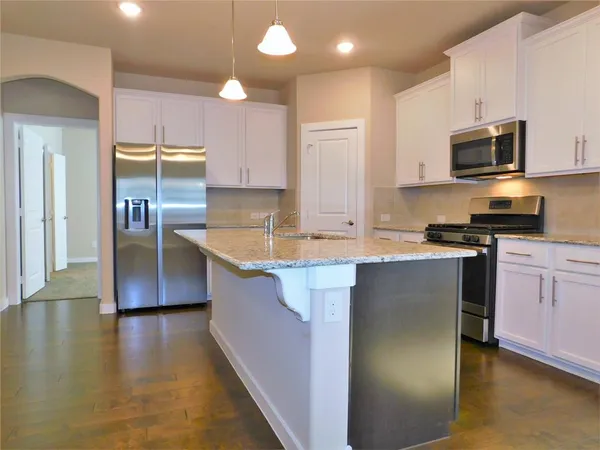 a kitchen with kitchen island granite countertop a sink stove and refrigerator
