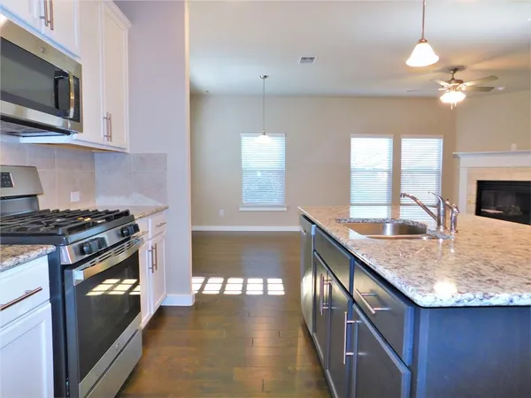 a kitchen with stainless steel appliances a sink a stove a refrigerator cabinets and a window