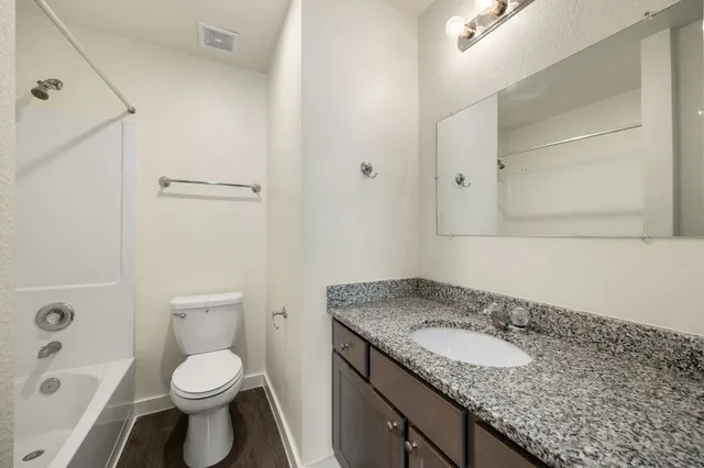 a bathroom with a granite countertop sink toilet and shower