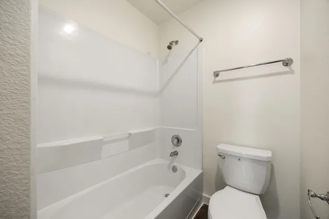 a white toilet sitting next to a bath tub