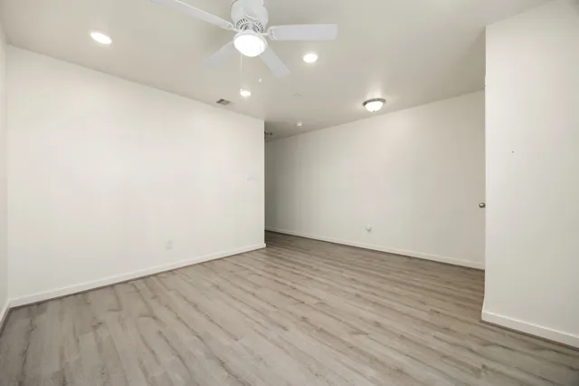 an empty room with wooden floor and fan