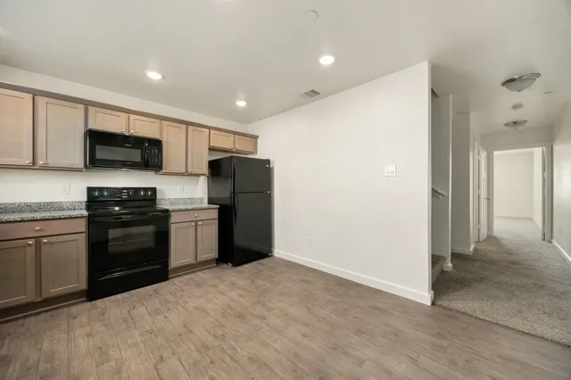 a kitchen with granite countertop a refrigerator and a stove top oven