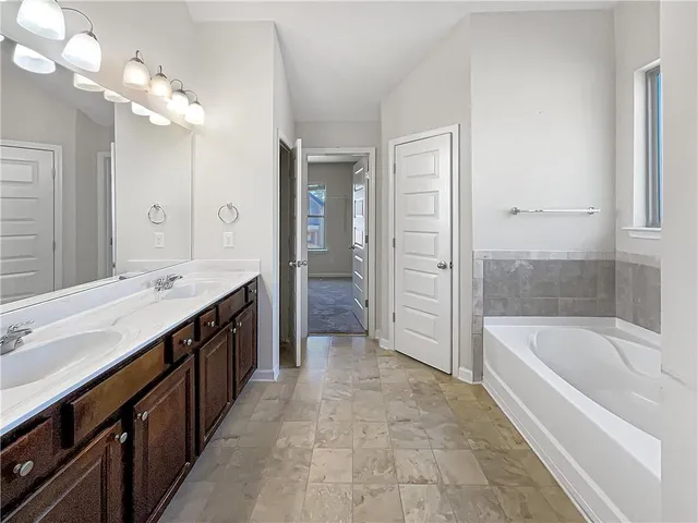 a spacious bathroom with a tub sink shower and mirror