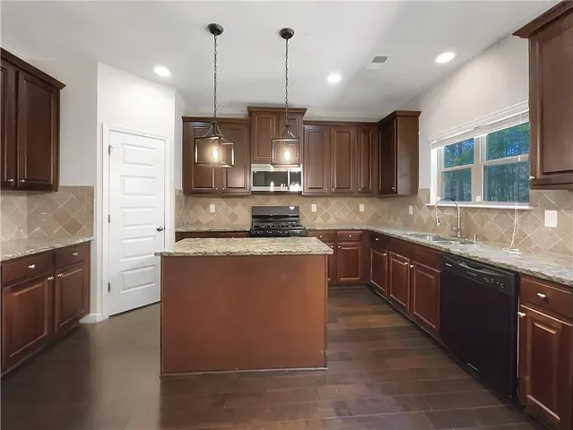 a kitchen with granite countertop kitchen island stainless steel appliances a stove sink and cabinets