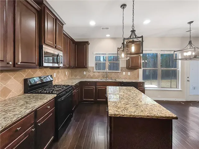a kitchen with granite countertop stainless steel appliances and wooden cabinets