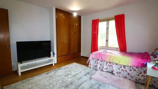 a bedroom with a bed and a flat tv screen on dresser