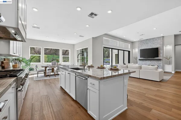 a kitchen with stainless steel appliances granite countertop a stove a sink and white cabinets