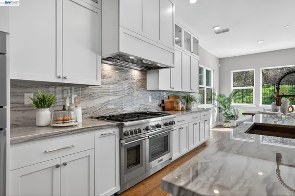 a kitchen with granite countertop white cabinets and stainless steel appliances