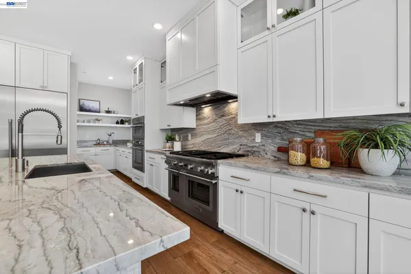 a large kitchen with stainless steel appliances a large counter top a sink a stove a refrigerator and a microwave