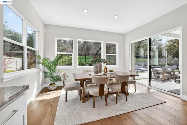 a dining room with kitchen island stainless steel appliances furniture large window and wooden floor