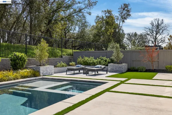a view of a swimming pool with a patio and a yard