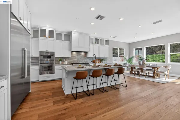 a kitchen with stainless steel appliances white cabinets a sink and chairs