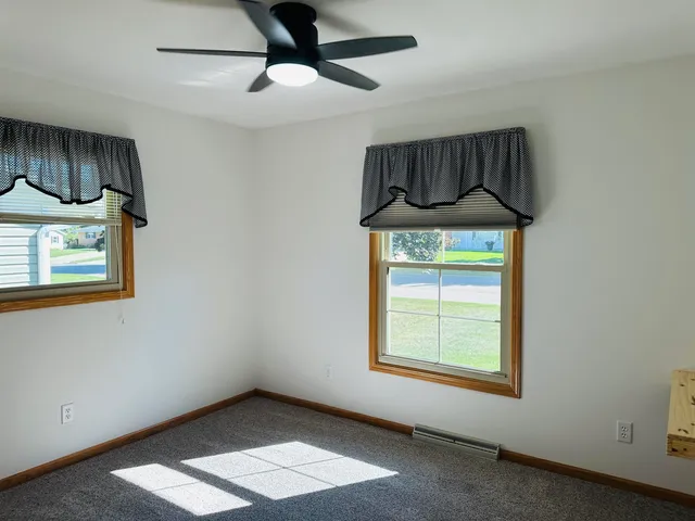 an empty room with a window and a ceiling fan
