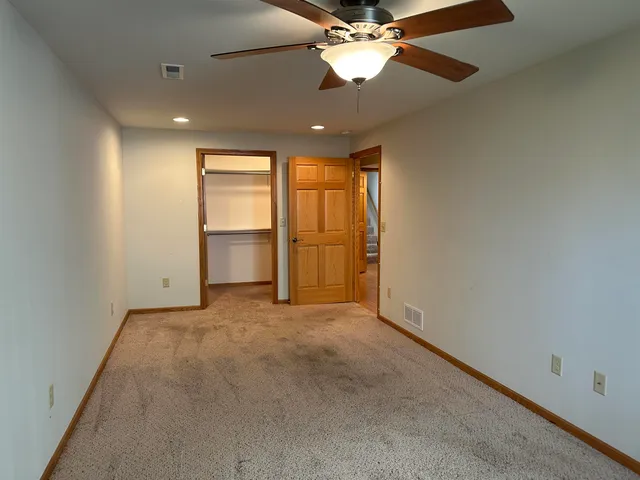 an empty room with windows and chandelier fan