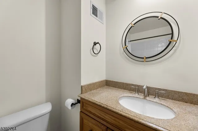 a bathroom with a granite countertop toilet a sink and a mirror