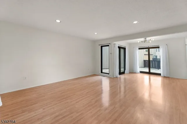 a view of an empty room with wooden floor and windows
