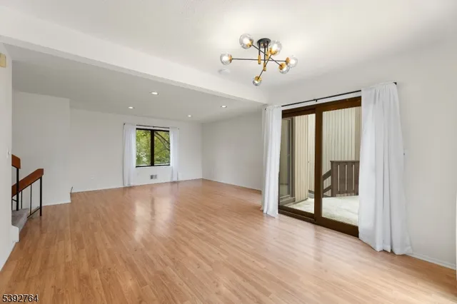 a view of an empty room and window with wooden floor