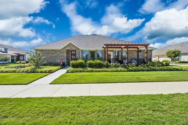 a view of house in front of a big yard with plants and large trees