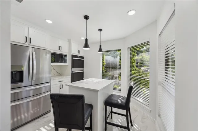 a kitchen with stainless steel appliances a refrigerator a stove a kitchen island with a stove and white cabinets