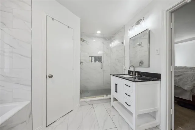 a bathroom with a granite countertop sink two mirror and a shower