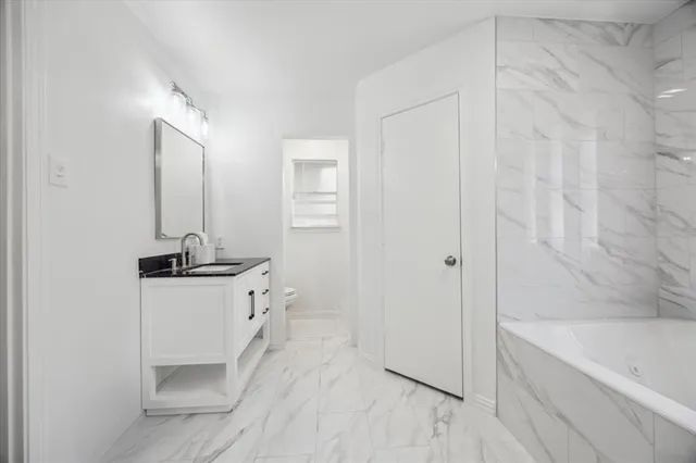 a bathroom with a granite countertop sink a mirror and a bathtub