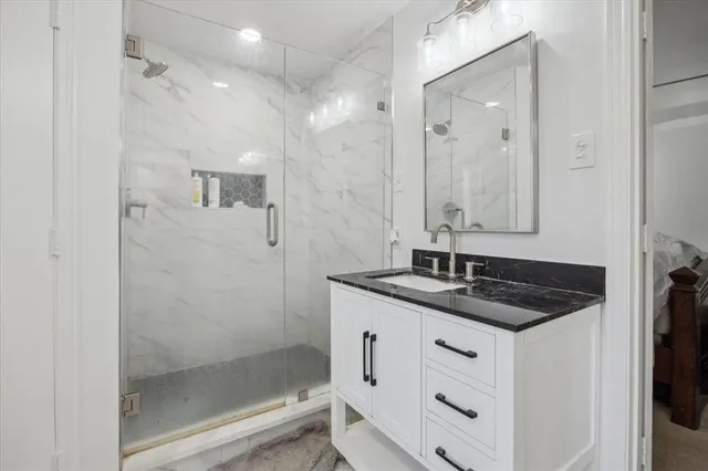 a bathroom with a granite countertop sink a mirror and shower